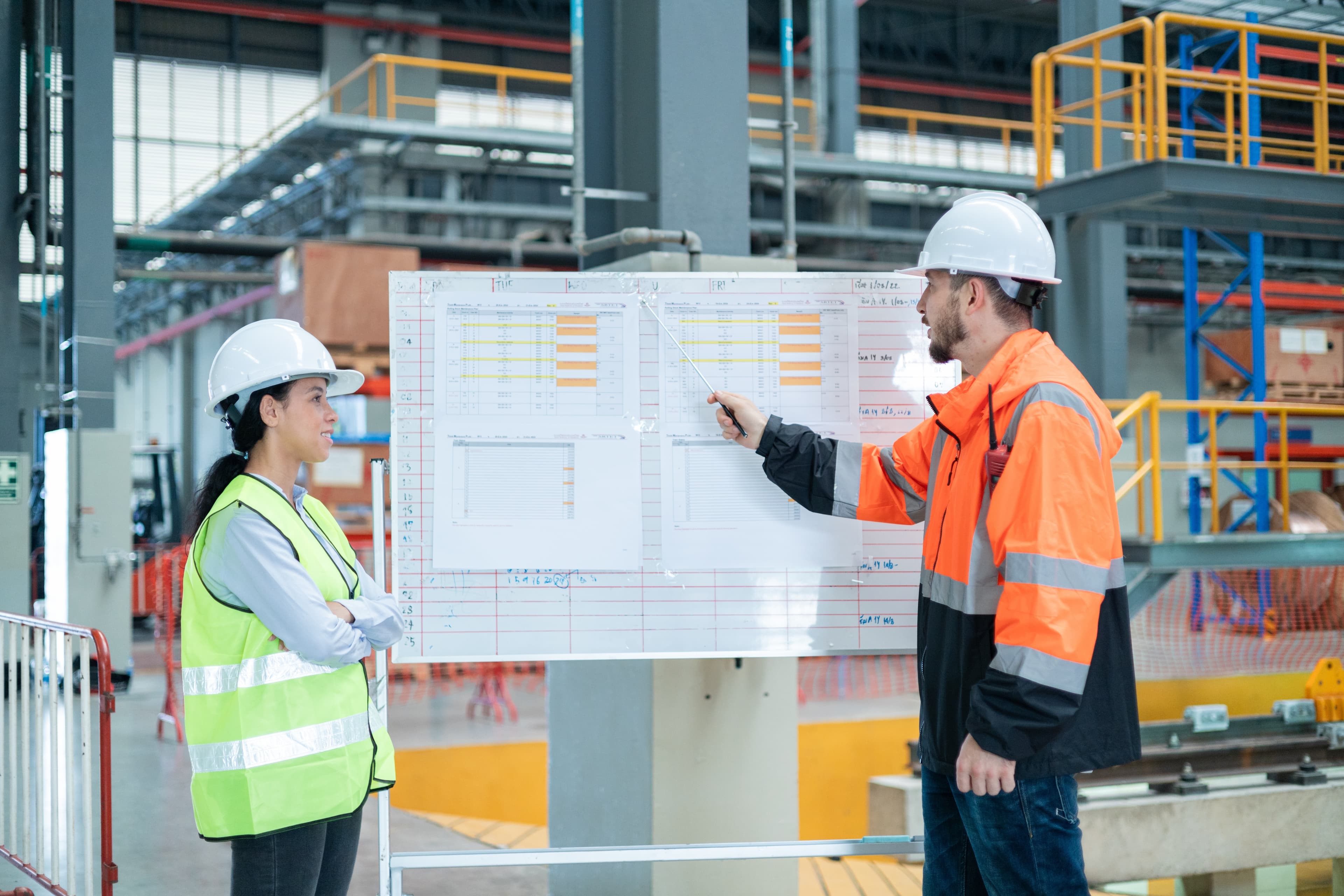 Two people stand at a whiteboard for construction project tracking