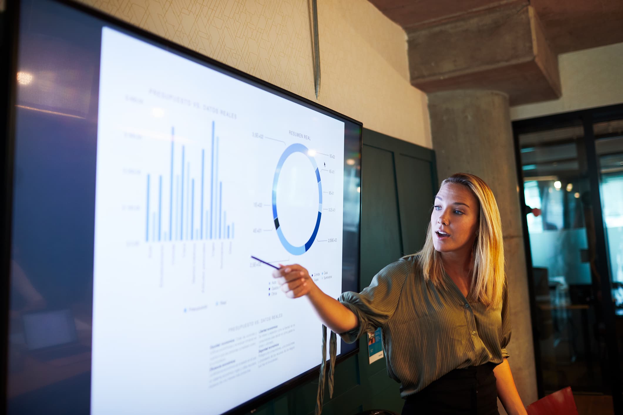 Woman standing in front of presentation, referencing charts and graphs
