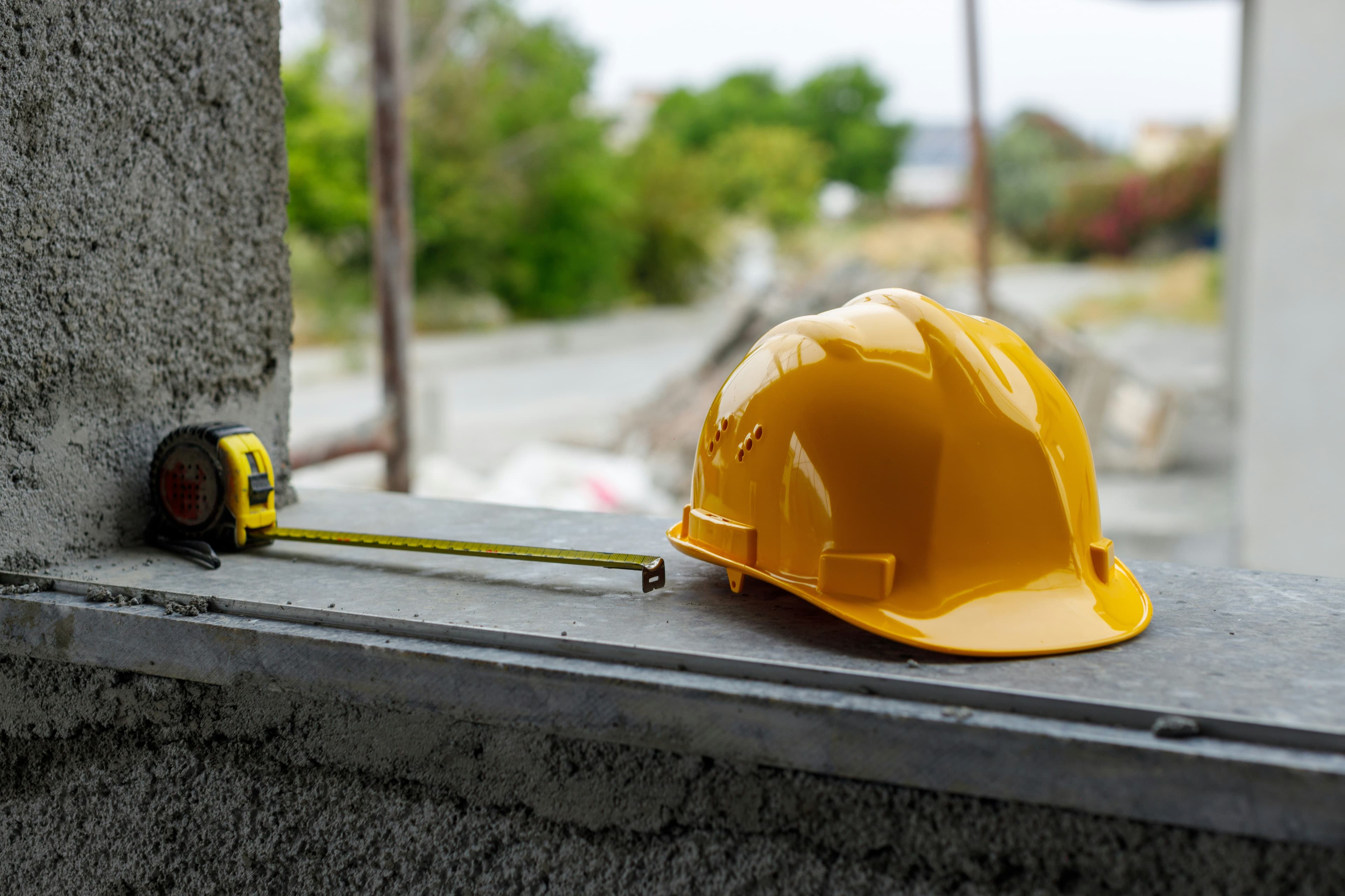 A hard hat and a measuring tape on a windowsill