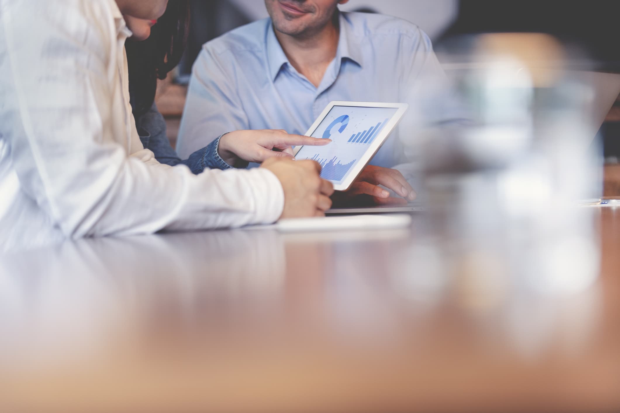 Two people at a desk reviewing a presentation on a tablet