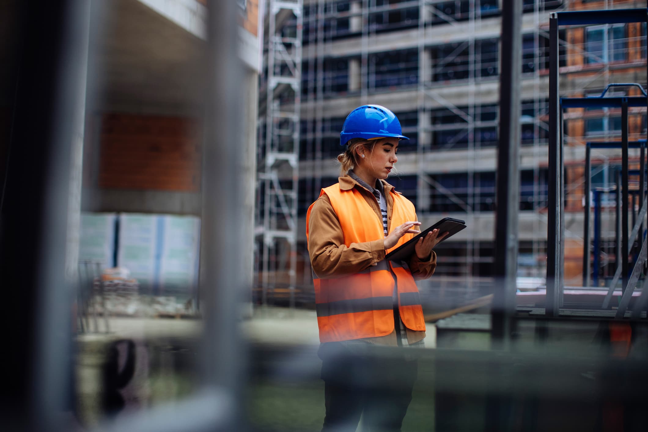 A worker references a tablet on a construction site